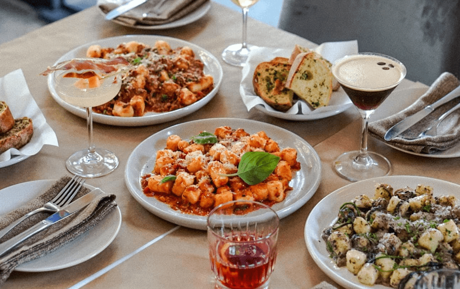A table with three different plates of gnocchi.